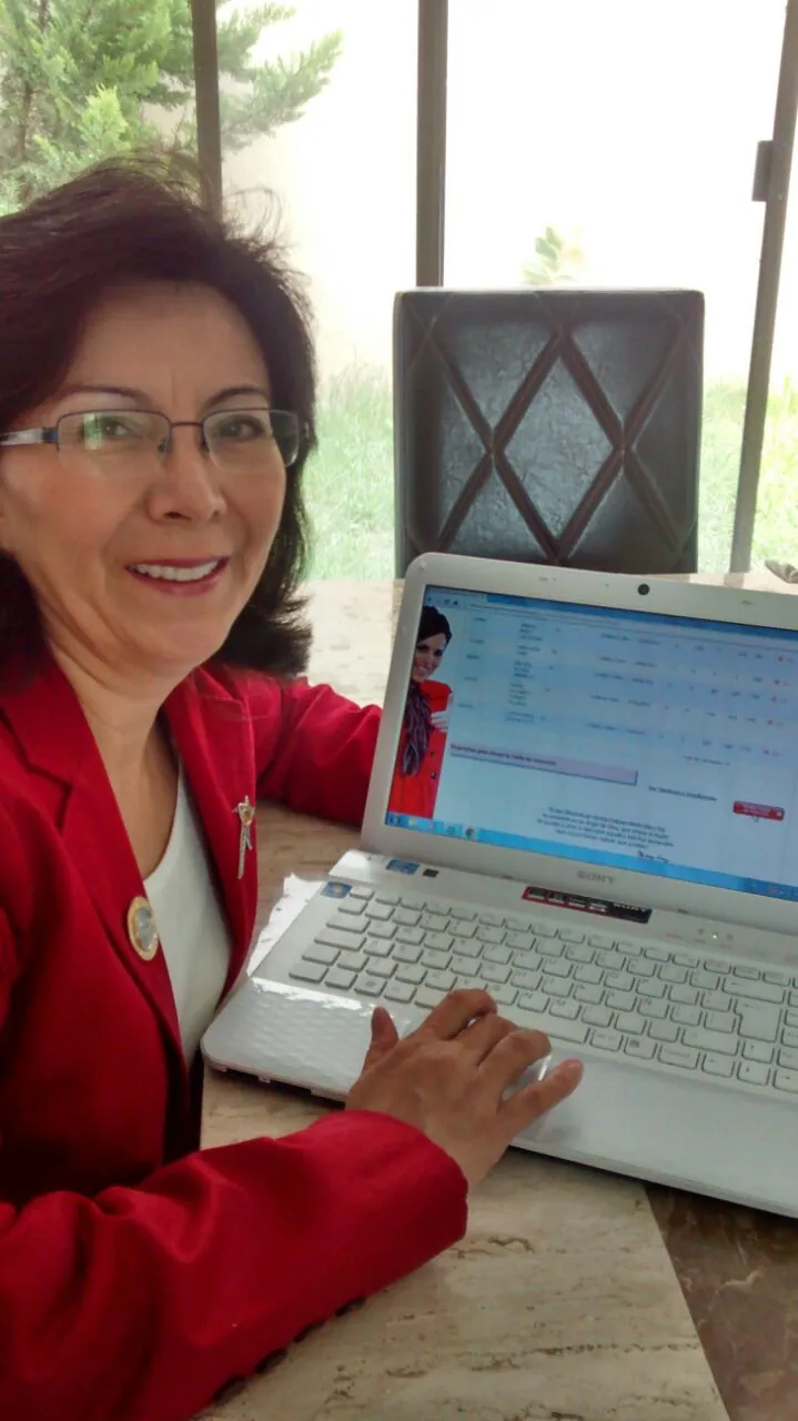 Patricia Moreno con saco rojo trabajando en su computadora portátil