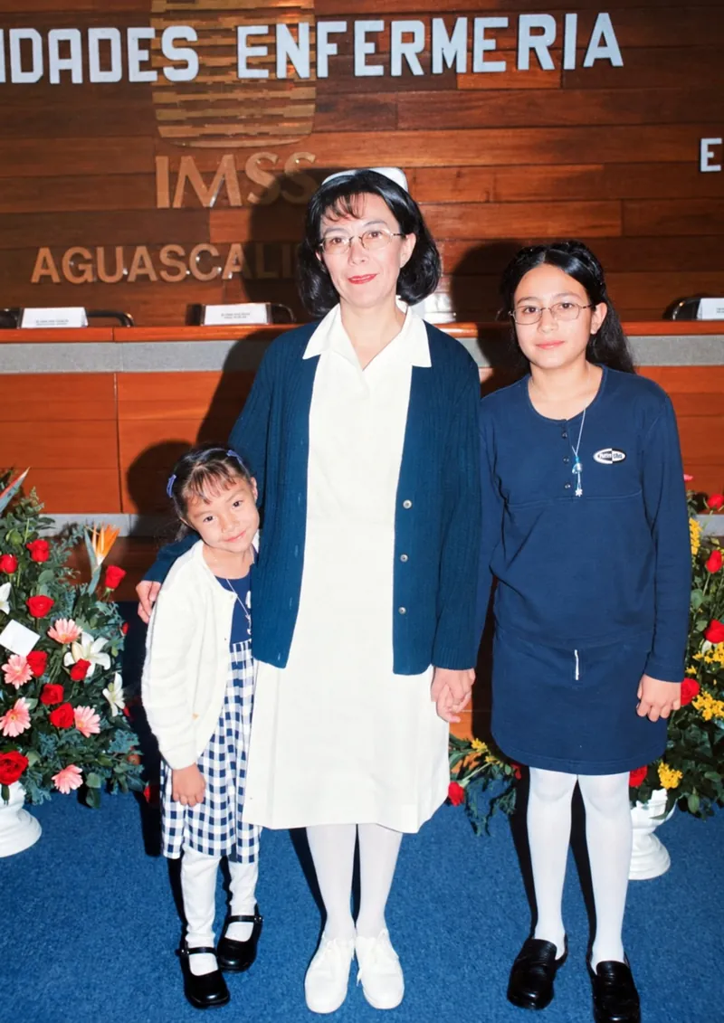 Patricia Moreno con uniforme de enfermería y sus dos hijas en un evento del IMSS