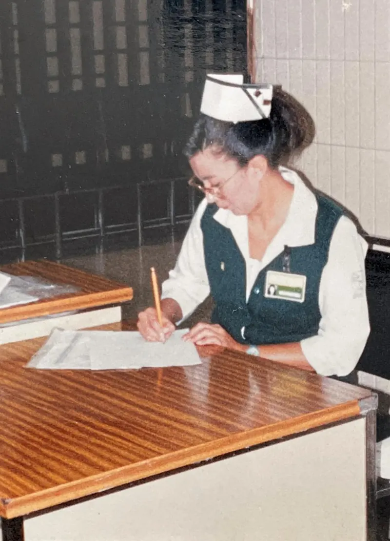 Patricia Moreno con uniforme de enfermería firmando en su escritorio