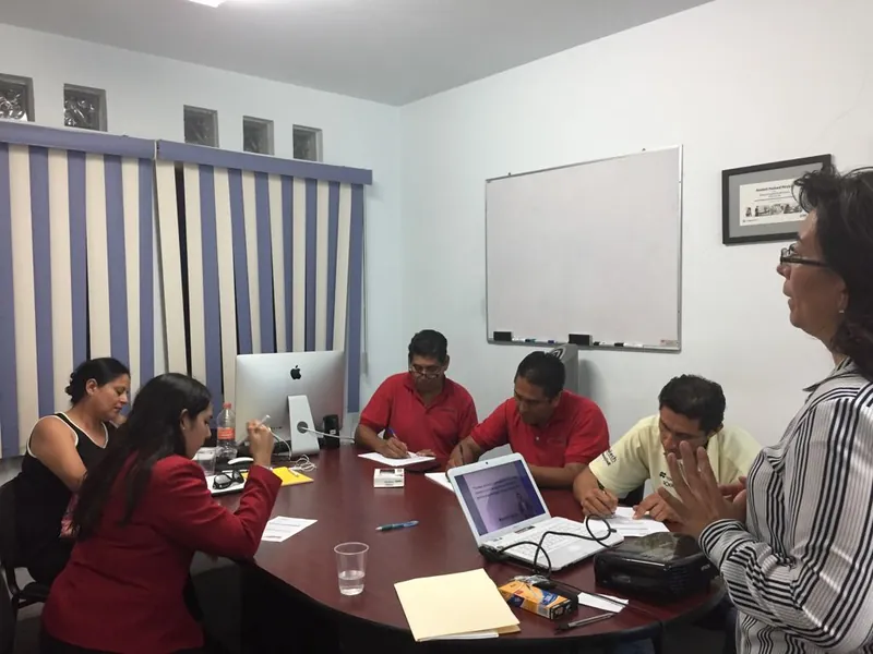 Reunión de trabajo alrededor de una mesa con computadoras portátiles
